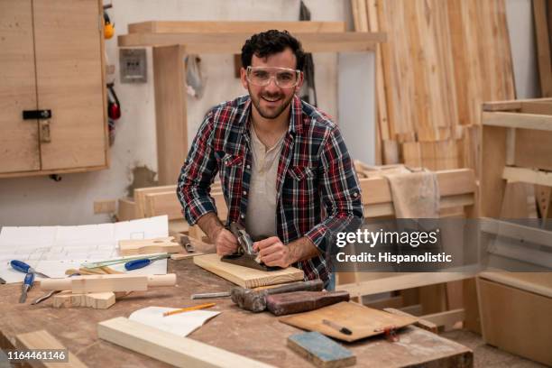 happy carpenter planning the wood at his workshop - man builds his own plane imagens e fotografias de stock