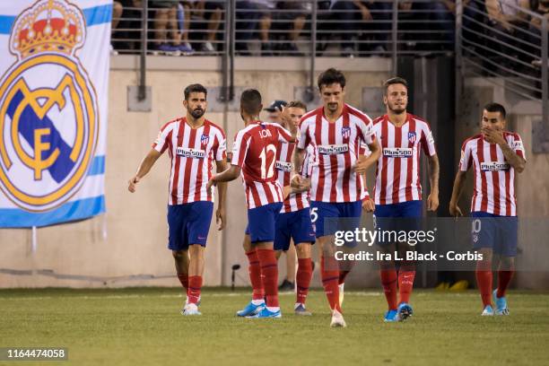 Diego Costa of Atletico Madrid leads his team in a victory march past a Real Madrid banner after scoring one of his four goals on the night during...