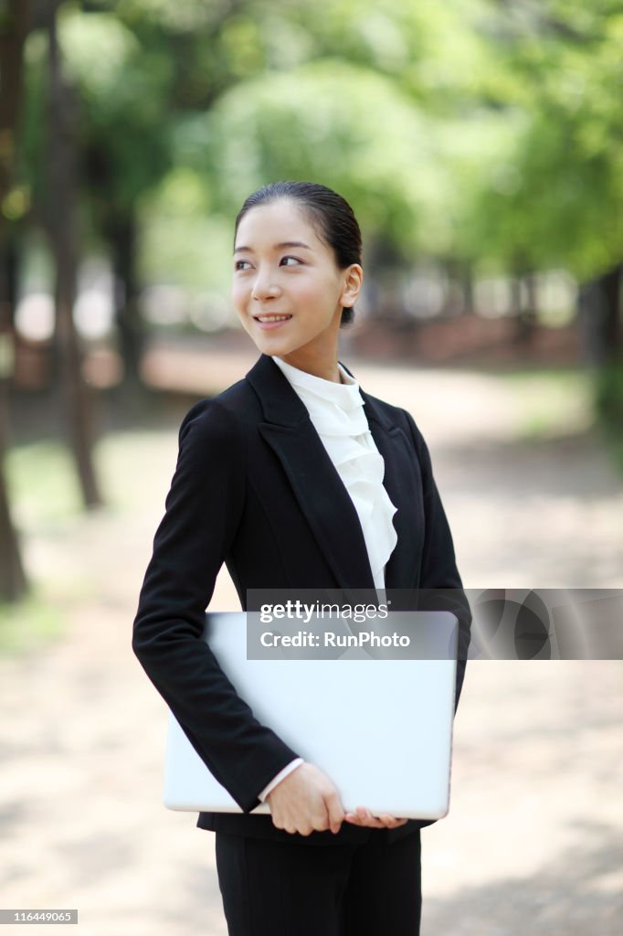 Business woman who has a computer in the park