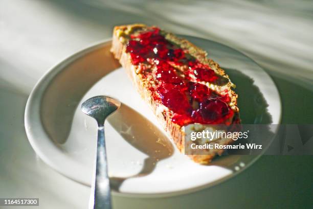 a slice of bread with butter and red jam - marmelade stock-fotos und bilder