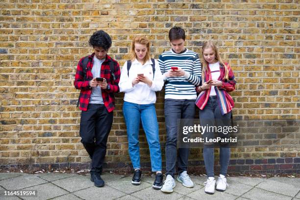 group of teenage friend focused on their own smartphone texting on social media - friends loneliness imagens e fotografias de stock