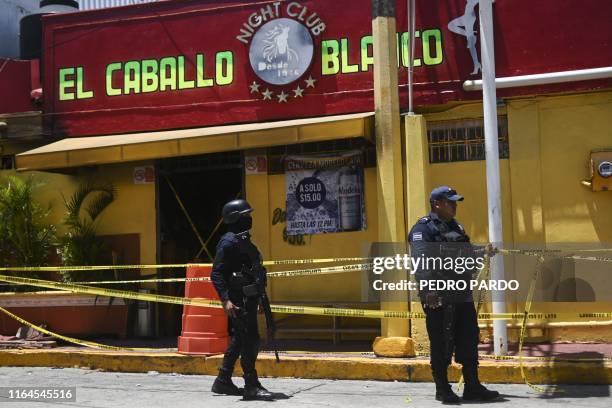 Police officers stand guard outside Caballo Blanco bar on August 28, 2019 where at least 26 people were killed and 11 badly wounded on the eve after...