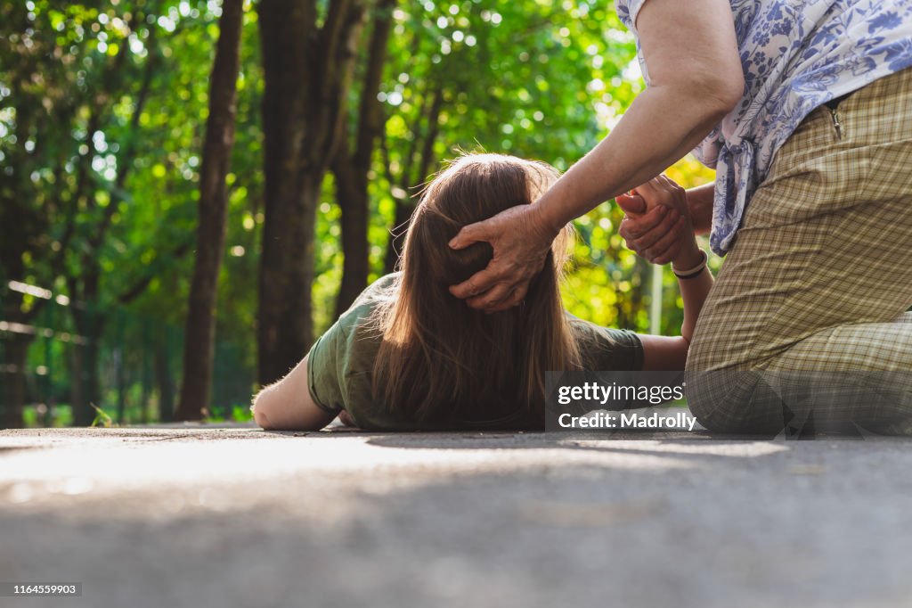 Gammal kvinna hjälper en svimmade flicka att komma tillbaka på fötterna