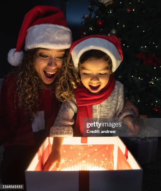 felice madre e figlio che aprono regali la vigilia di natale - sorpresa regalo foto e immagini stock