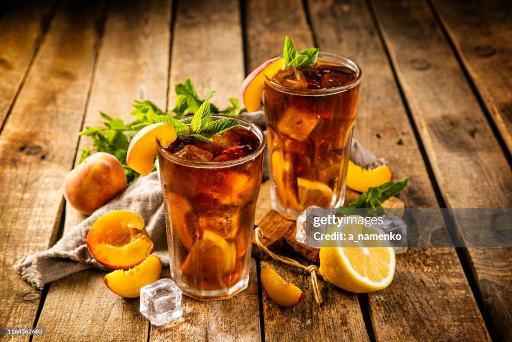 Ice tea and ingredients in glasses on wood background