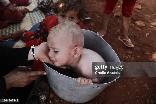 Syrian baby bathing in a bucket outside a makeshift tent among olive trees on their way from Syrias de-escalation zones in Idlib, Syria on August 28,...