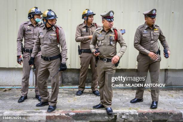 Policemen escorting Myanmar prisoners Zaw Lin and Win Zaw Tun watch at a court compound in Nonthaburi on August 29, 2019. - Two Myanmar migrant...