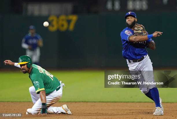 Danny Santana of the Texas Rangers completes the double-play throwing over the top of Marcus Semien of the Oakland Athletics in the bottom of the...