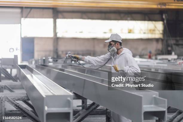 man painting metal in factory - lacquered stock pictures, royalty-free photos & images