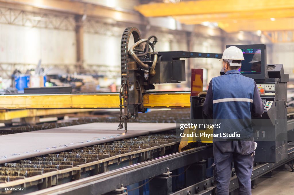 Trabajador de acero en la máquina cortadora de plasma CNC