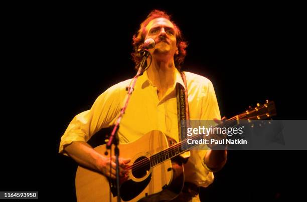 American Folk musician James Taylor plays acoustic guitar as he performs onstage at the Poplar Creek Music Theater, Hoffman Estates, Illinois, June...