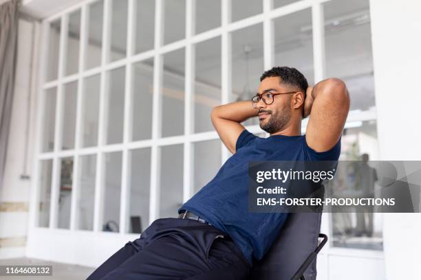 relaxed man sitting in his office - hands behind head stock pictures, royalty-free photos & images