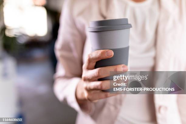 close-up of a businesswoman holding recycable takeaway coffee cup - travel mug stock pictures, royalty-free photos & images