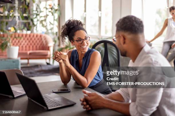 businessman looking at female manager in her office - kleine personengruppe stock-fotos und bilder