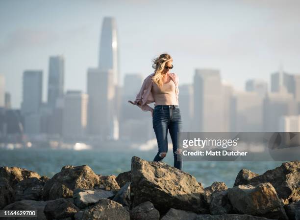 woman looking at san francisco skyline and bay bridge - treasure island san francisco stock pictures, royalty-free photos & images