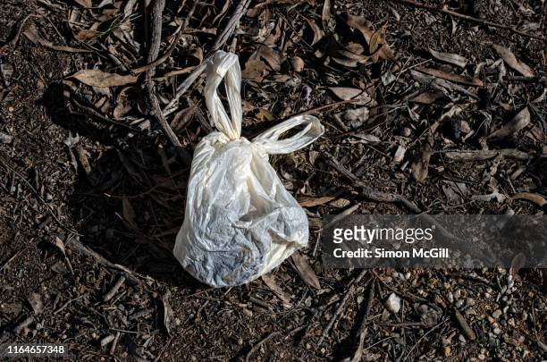 tied plastic bag of dog feces abandoned in bush land - desert dog stockfoto's en -beelden