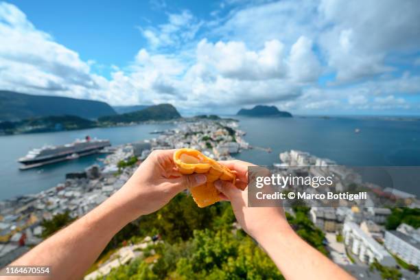 personal perspective of man eating a pancake looking at view in alesund, norway - norway food stock pictures, royalty-free photos & images