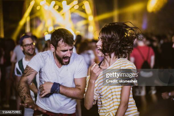 unbeschwertes paar mit spaß beim tanzen auf musikfestival bei nacht. - rock festival stock-fotos und bilder