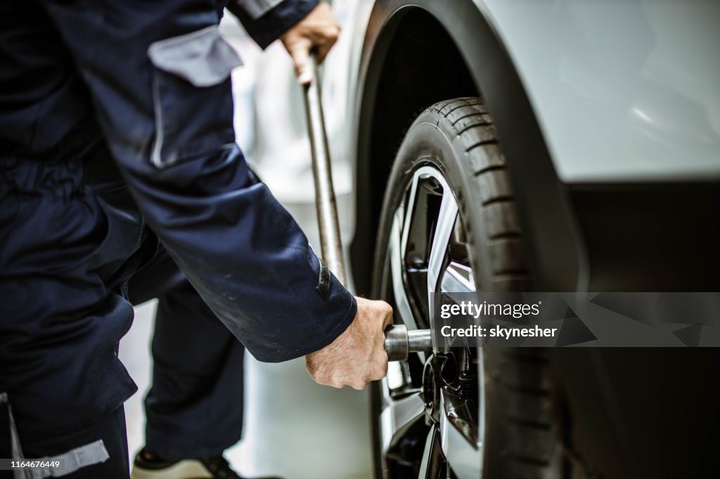 Feche acima de um reparador que muda a roda e o pneu em uma oficina.