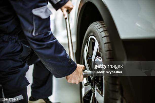 feche acima de um reparador que muda a roda e o pneu em uma oficina. - tighten - fotografias e filmes do acervo