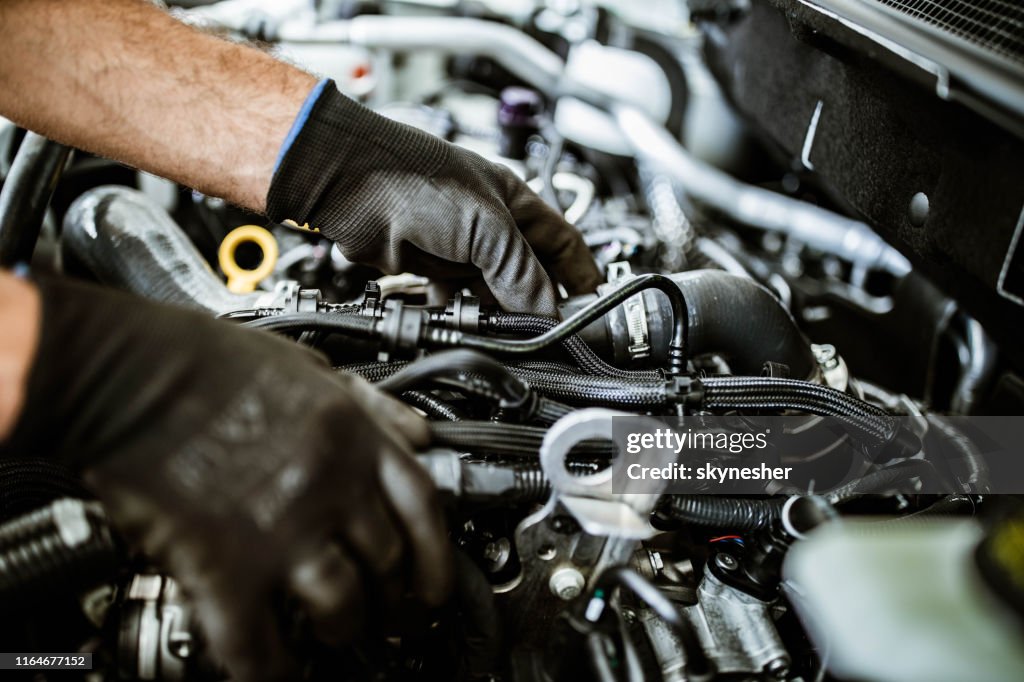 Nahaufnahme eines Mechanikers, der die Autopumpe in einer Werkstatt untersucht.