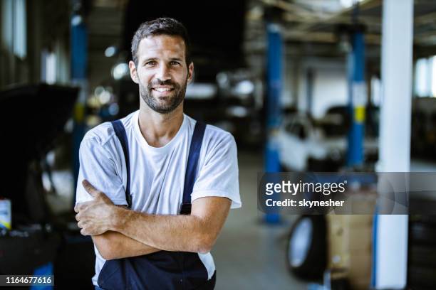 glücklicher mechaniker mit gekreuzten armen in autowerkstatt. - mechanic portrait stock-fotos und bilder
