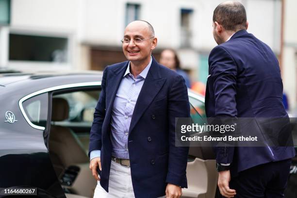 Guest wears a blue and white pinstriped shirt, a navy blue jacket, outside Hermes, a light khaki woven belt, white pants, during Paris Fashion Week -...