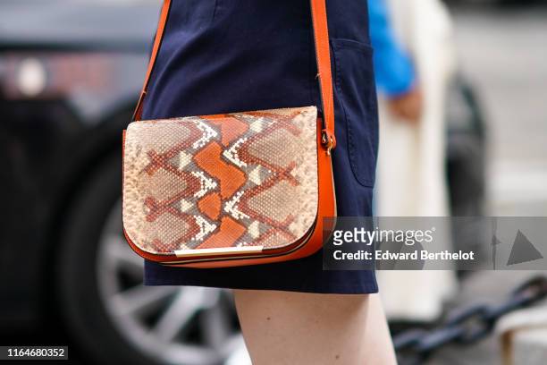 Guest wears a navy blue mini dress, an orange python pattern bag, outside Hermes, during Paris Fashion Week - Menswear Spring/Summer 2020, on June...