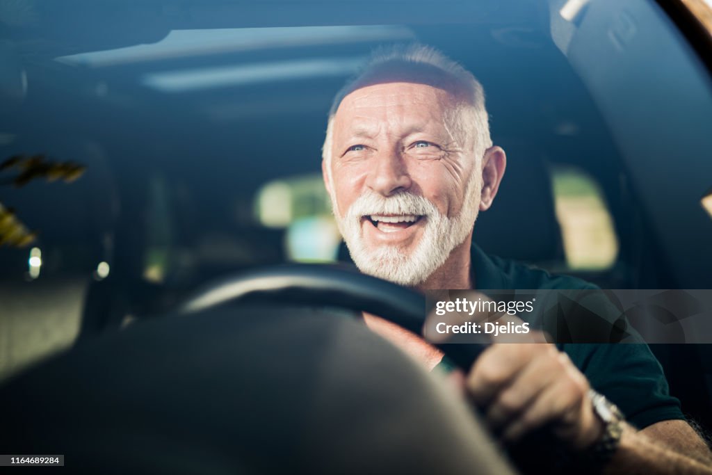 Fröhlicher Senior Mann mit Spaß in seinem neuen Auto.
