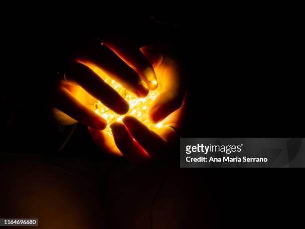 fairy lights illuminating a woman's hands - luce alla fine del tunnel foto e immagini stock