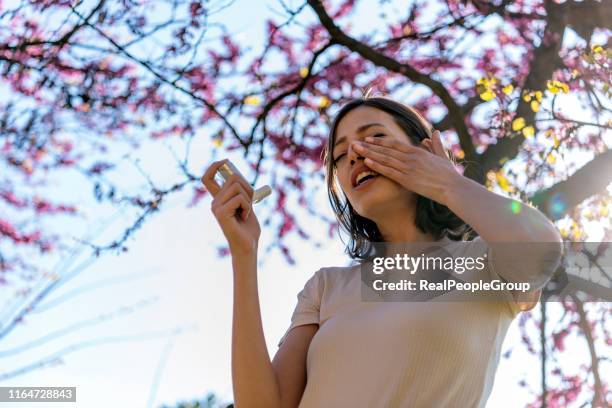 mujer usando inhalador de asma al aire libre - asmático fotografías e imágenes de stock