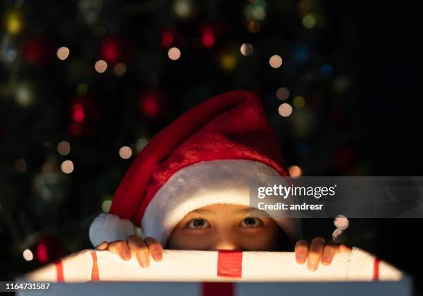 girl getting a sneak peek of a christmas gift - gift excitement stock pictures, royalty-free photos & images