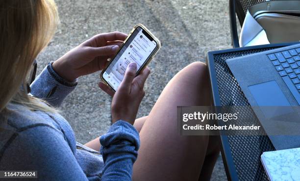 Young woman uses her smartphone as she sits outside a coffee shop in Jacksonville, Oregon.
