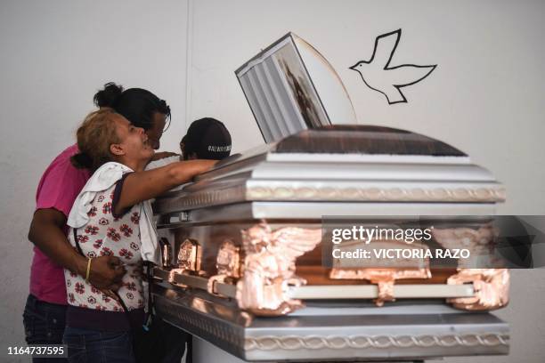 Relatives and friends mourn leaning against the coffin of Xochitl Nayeli Irineo, one of the 28 victims of the attack at the Caballo Blanco bar ,...