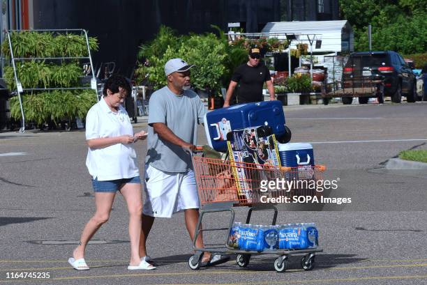 People push a shopping cart of hurricane supplies to their car in a Home Depot parking lot in preparation for the arrival of Hurricane Dorian which...