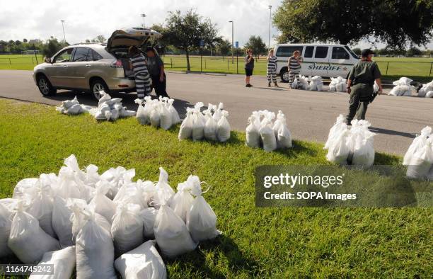 Supervised work crew of female jail prisoners loads sandbags into a vehicle for a local resident in preparation for the arrival of Hurricane Dorian...