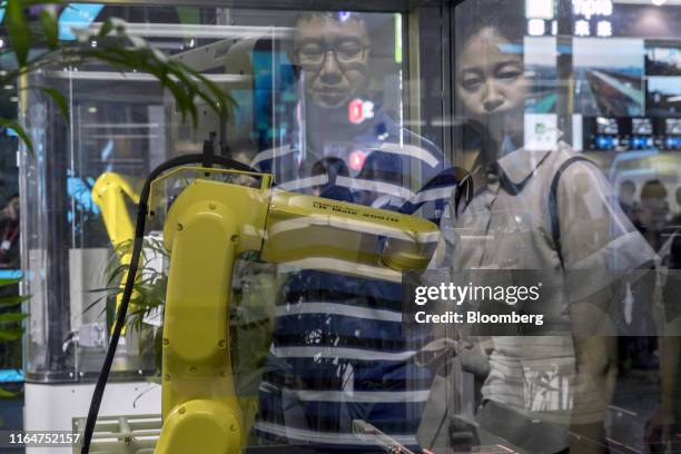 Attendees are reflected in the display case of a Fanuc Crop. LR Mate 200iD human arm sized mini robot being demonstrated at the World Artificial...