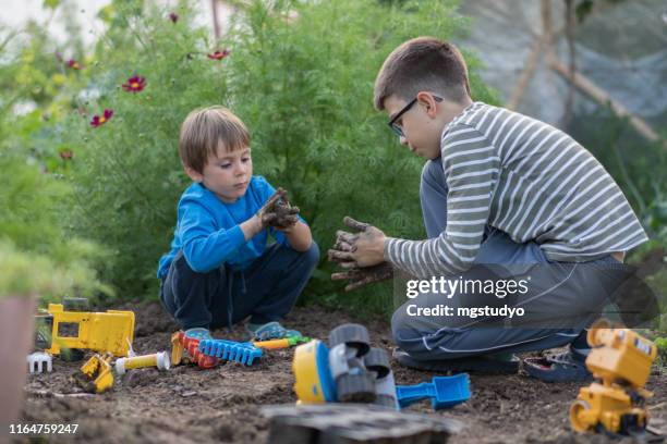 young brothers plays in the mud with his toy truck - toy truck stock pictures, royalty-free photos & images