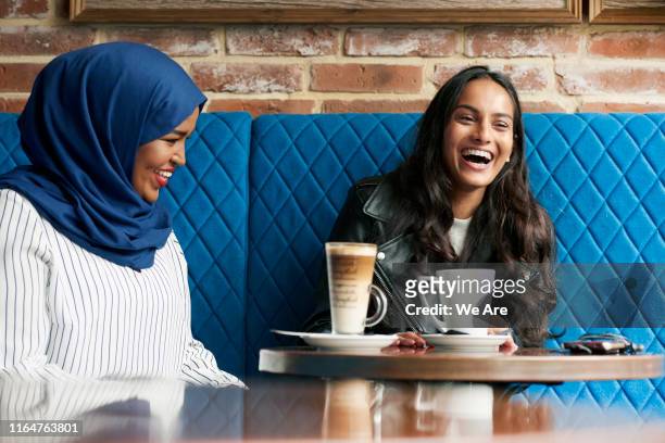 friends laughing and drinking coffee in a cafe - indulgence stock pictures, royalty-free photos & images