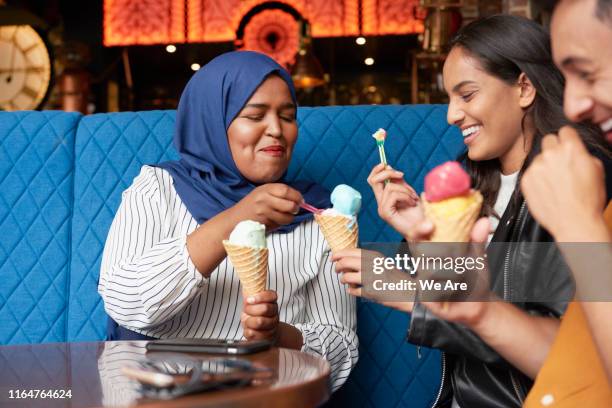 friends sharing ice cream in ice cream parlor - sharing imagens e fotografias de stock