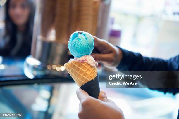 man scooping ice cream onto cone - cornet stockfoto's en -beelden