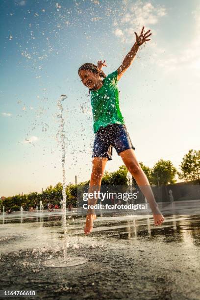 little girl playing in fountains at outdoor splash pad - fountain stock pictures, royalty-free photos & images