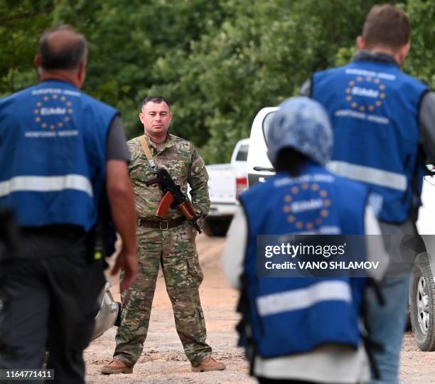 Members of European Union monitoring mission approach a Georgian special police officer as he patrols Georgian - South Ossetian border at a check...