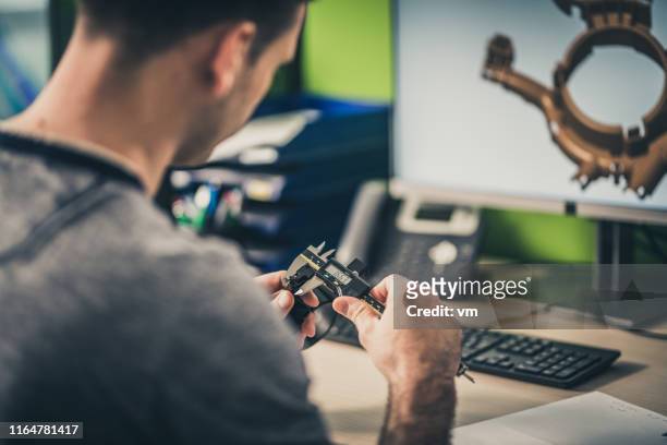 engineer measuring a machine part while working on a 3d model - machine part stock pictures, royalty-free photos & images