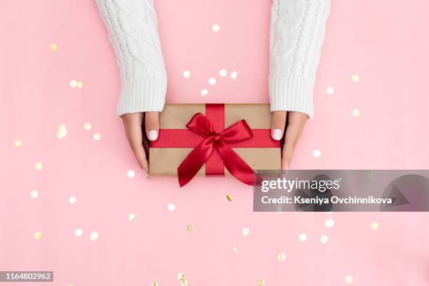 womans hands holding gift or present box decorated confetti on pink pastel table top view. flat lay composition for birthday or wedding. - wedding gift stockfoto's en -beelden