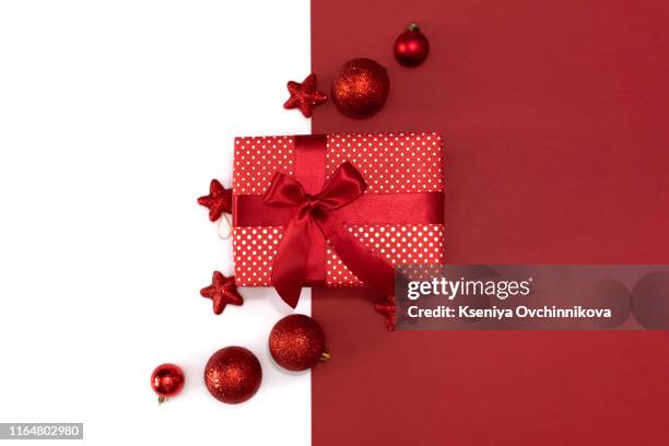 christmas gifts presents on red background. simple, classic, red and white wrapped gift boxes with ribbon bows and festive holiday decorations. - holiday gift stock-fotos und bilder