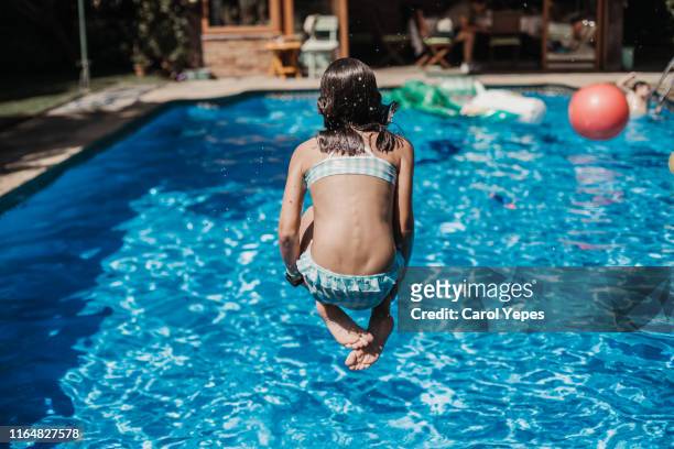 girl jumping into swimming pool - lanzarse al agua salpicar fotografías e imágenes de stock
