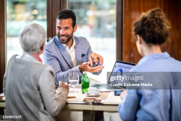 finanzberaterin erklärt zwei geschäftspartnerinnen in einem restaurant die geschäftsstrategie - geldfluss stock-fotos und bilder