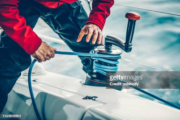 segler wickelseil auf winde mit händen - segeln stock-fotos und bilder