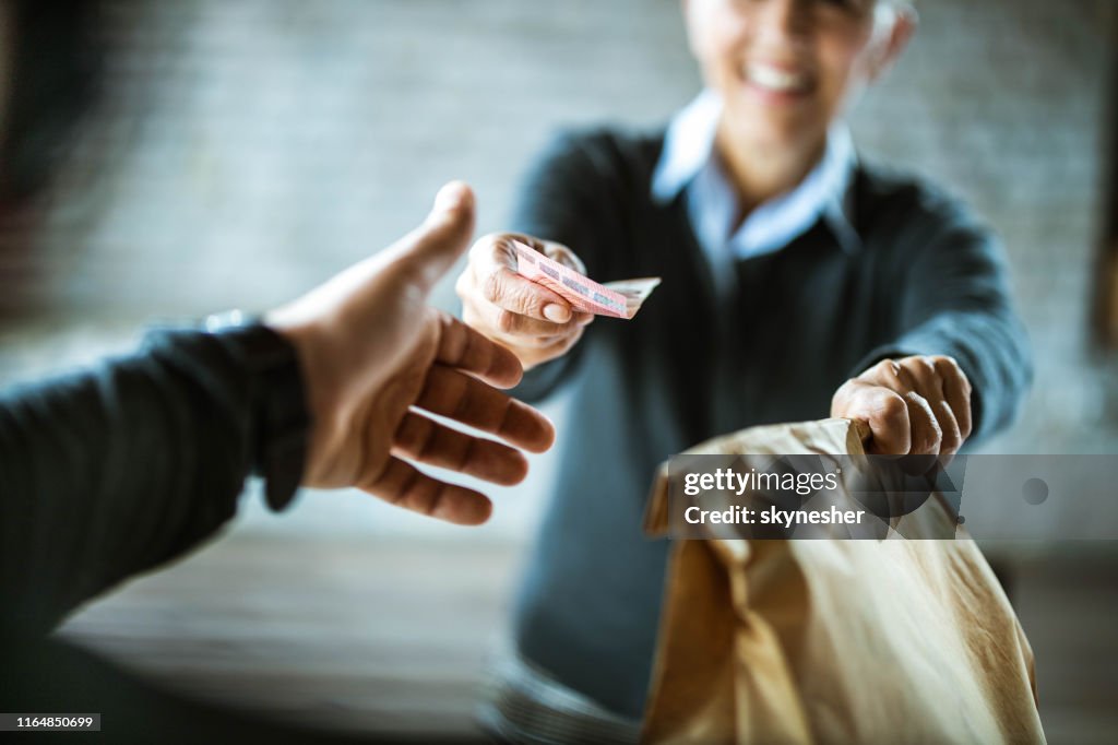 Primer plano de una mujer dando dinero a la repartidora.